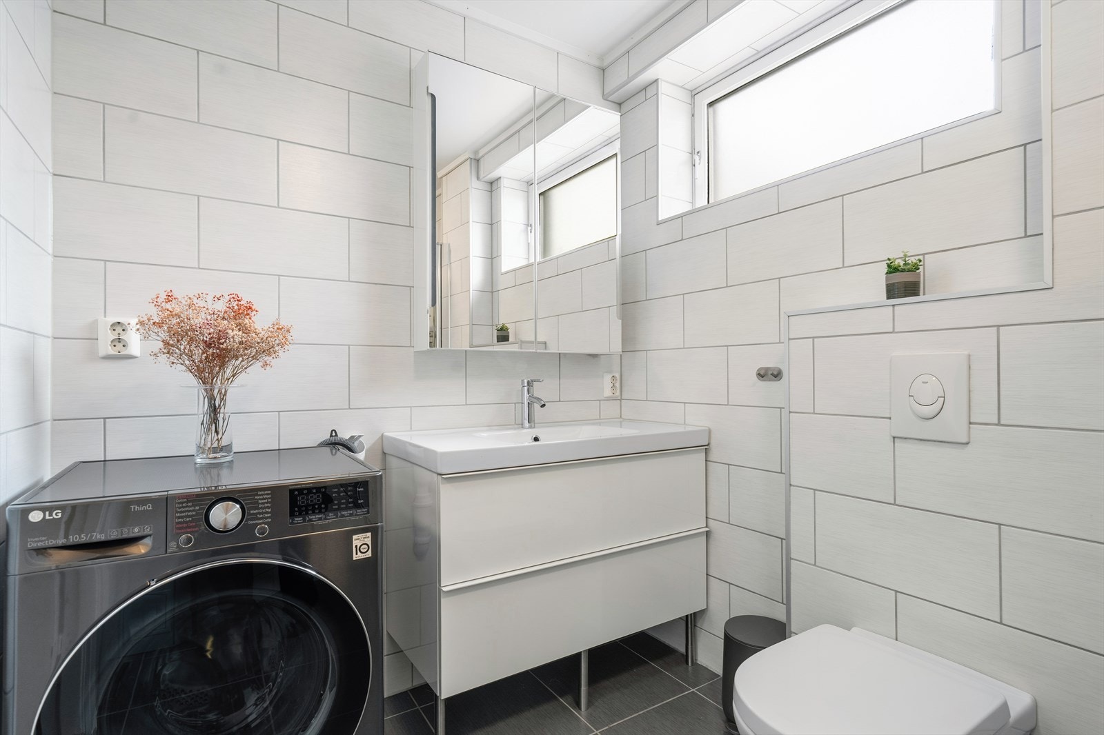 Badet er praktisk innredet med moderne baderomsinnredning, vegghengt toalett og opplegg for vaskemaskin. Galleribilde