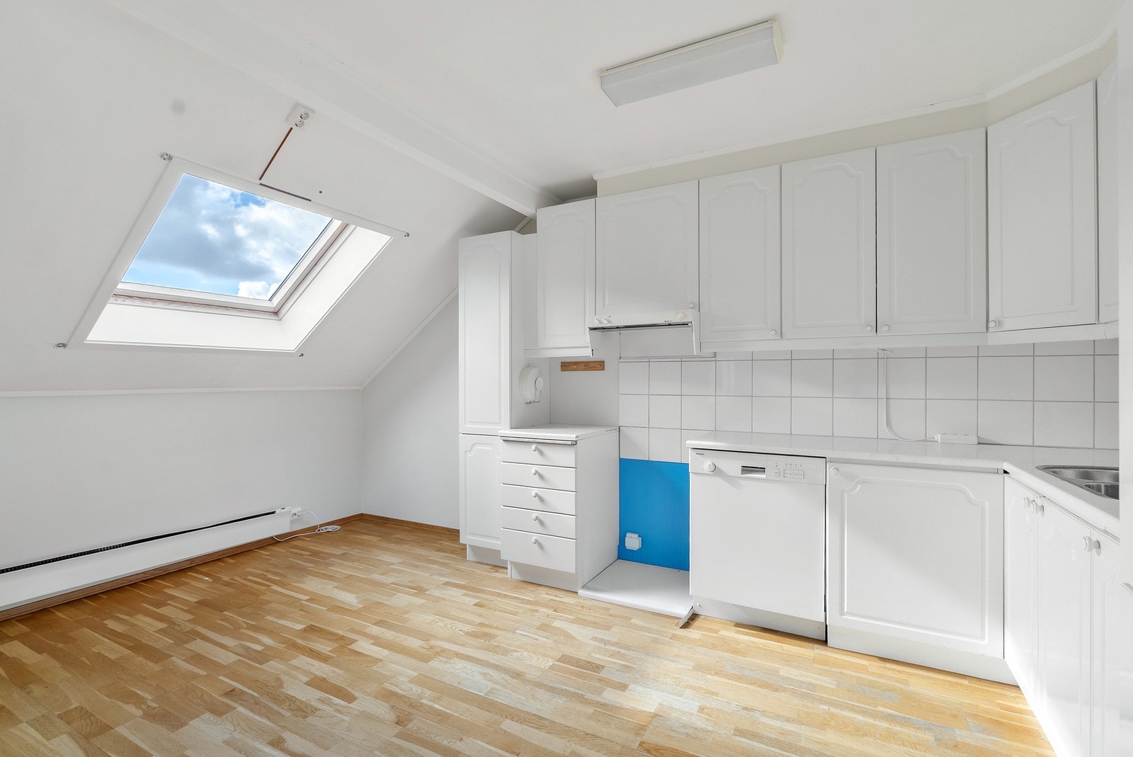 Åpen stue- og kjøkkenløsning med gjennomgående parkettgulv. Et Velux takvindu gir rikelig med dagslys til kjøkkenet. Galleribilde