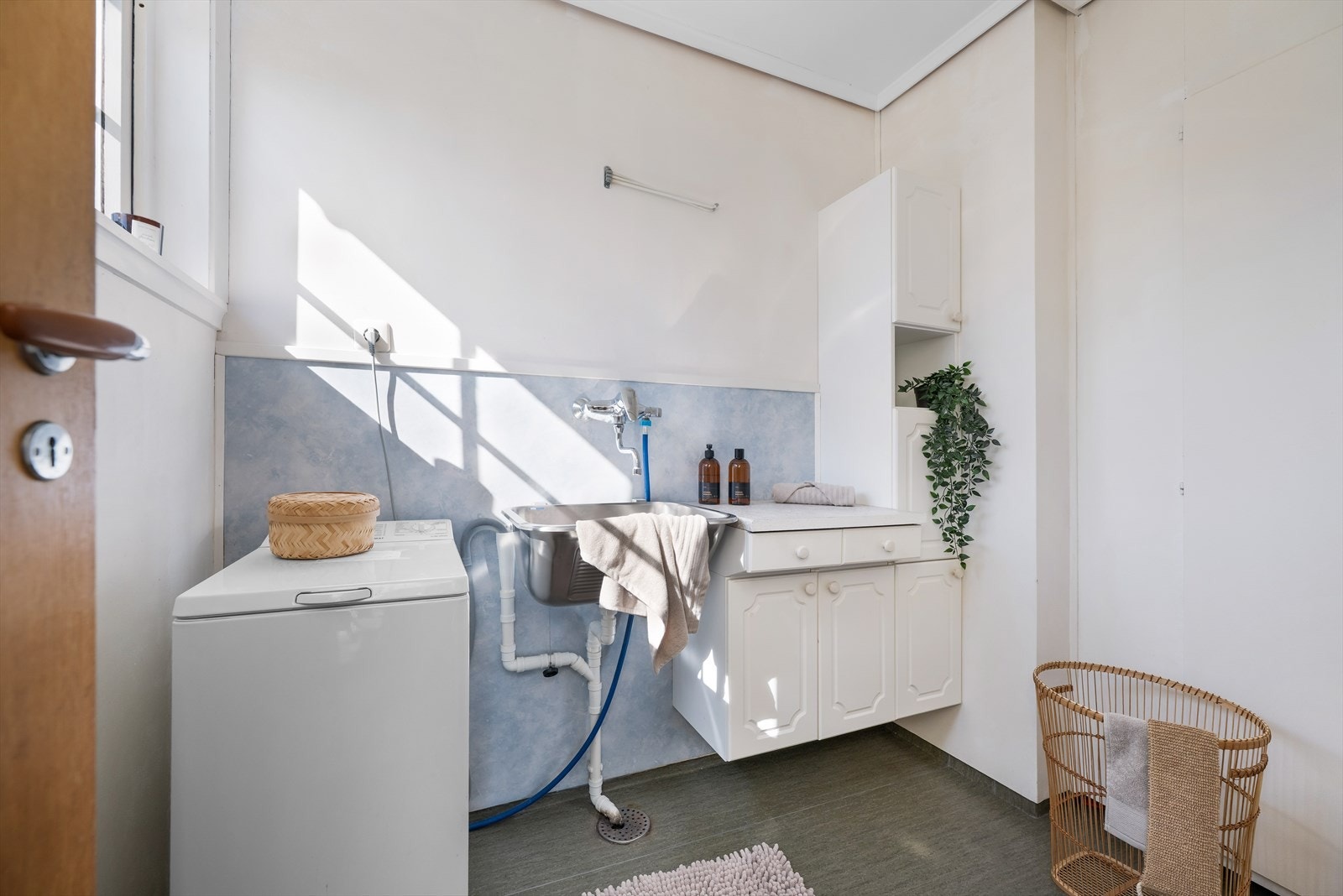 Boligen har et eget praktisk vaskerom med opplegg for vaskemaskin og utgang til terrasse. Galleribilde