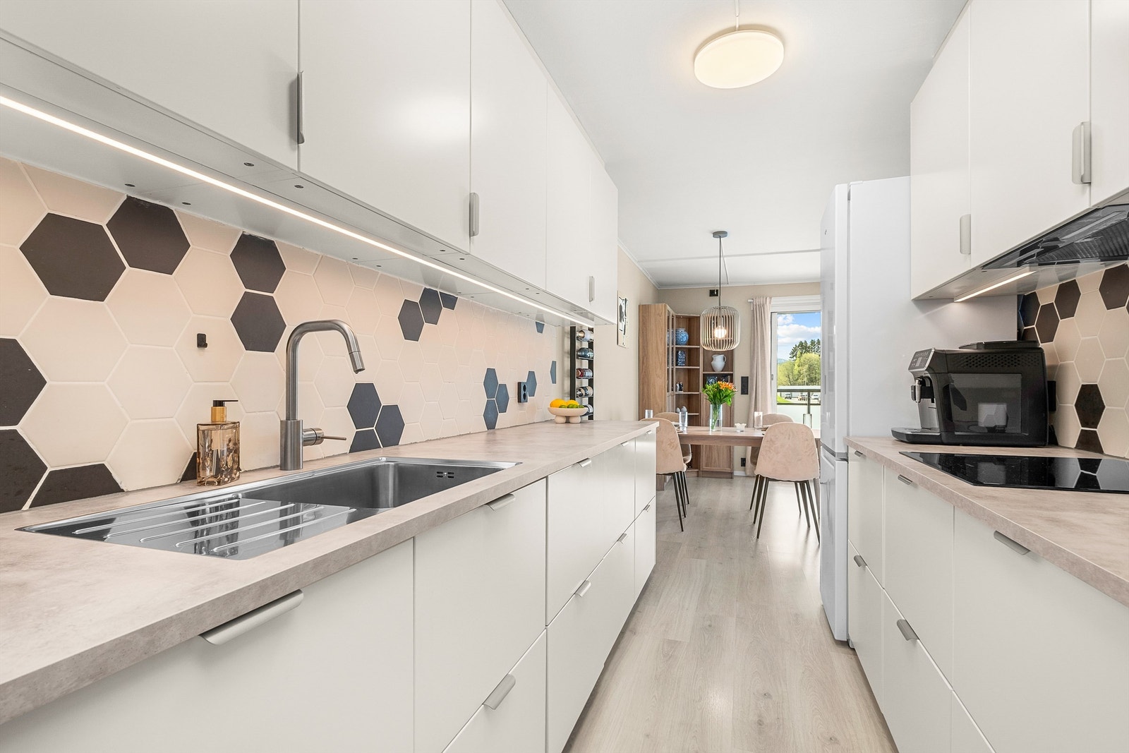 Kjøkkenet ligger naturlig tilbaketrukket fra stuen og er innredet med lyse slette flater og benkeplate av laminat. Her har man rikelig med skap- og benkeplass å boltre seg på! Galleribilde