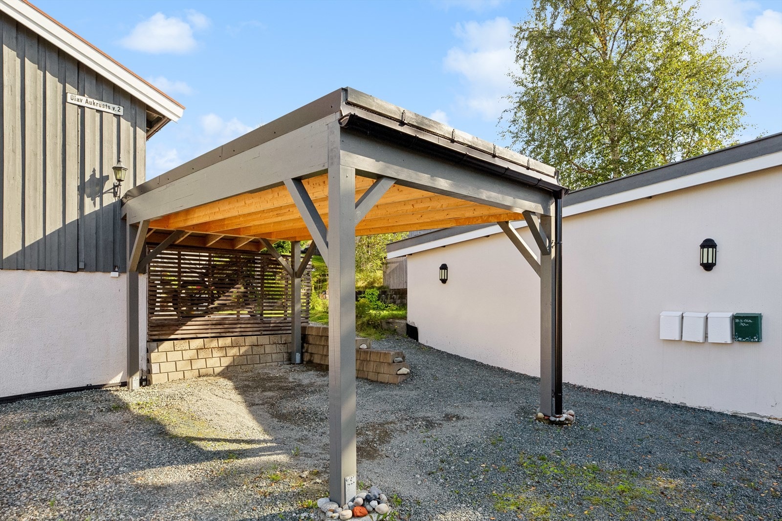 Egen carport som ble oppført i 2022. Taket strekker seg delvis inn over platting for ekstra lagringsplass. Galleribilde