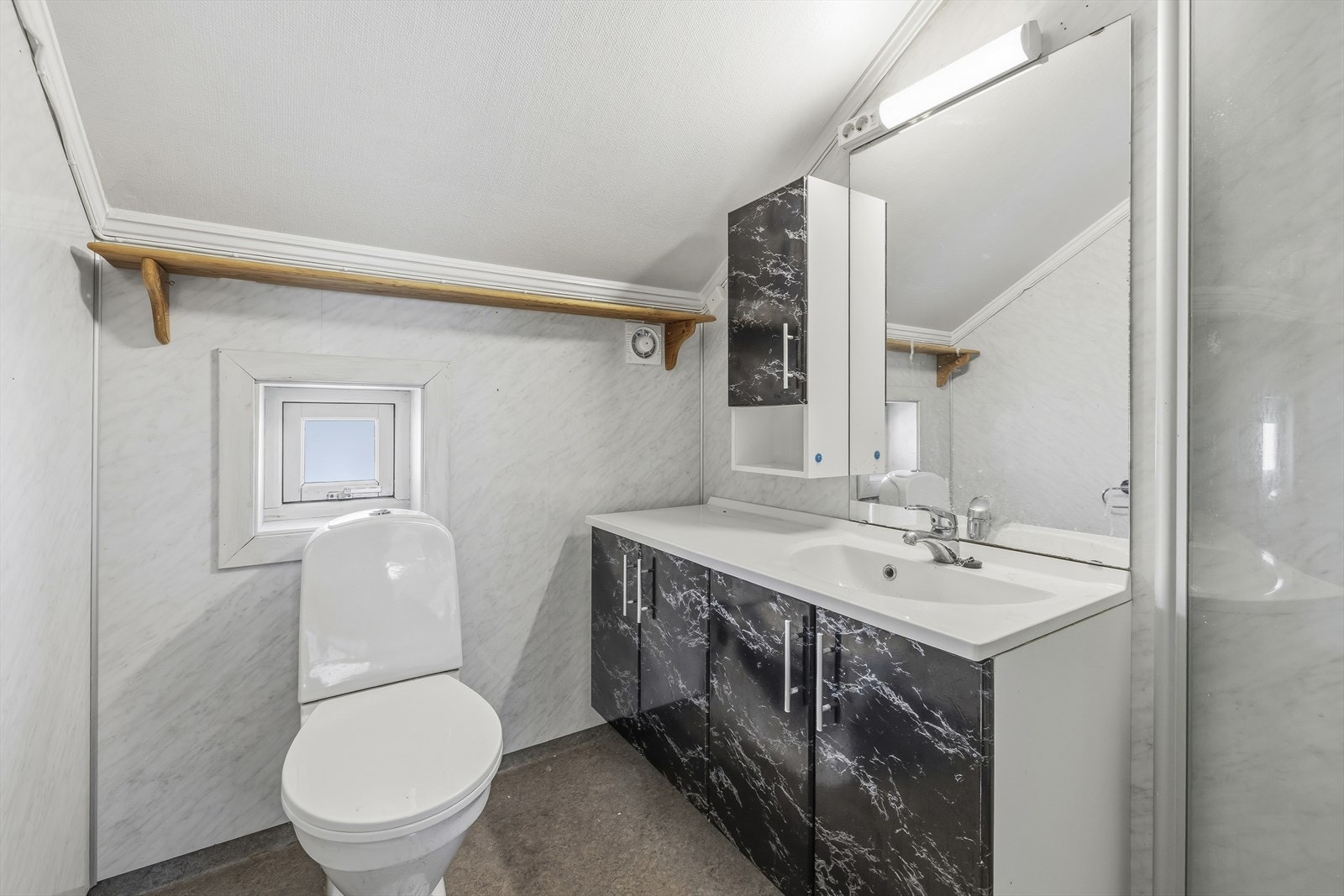 Badet er innredet med toalett, servant med skap og dusjkabinett. Galleribilde
