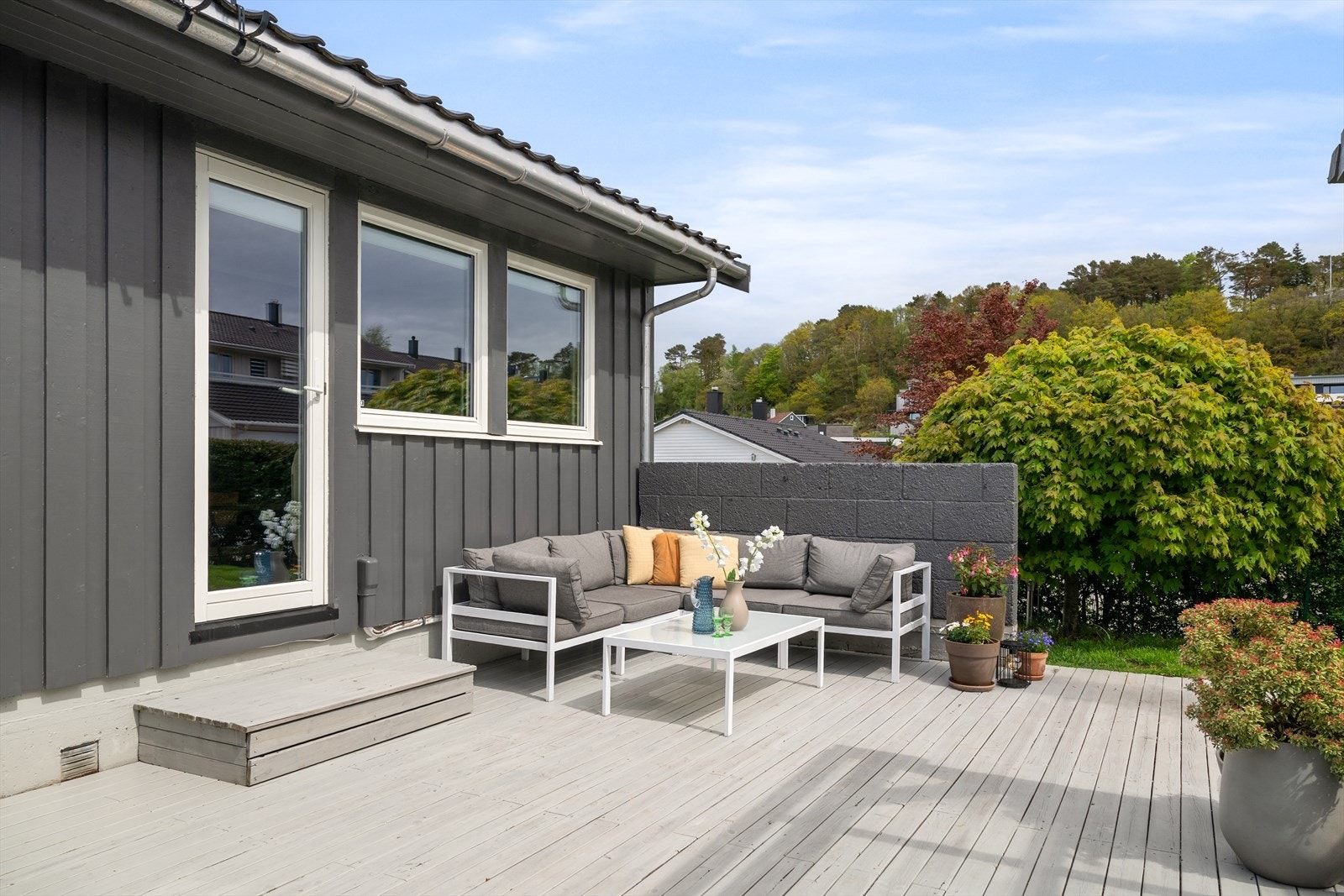 Uteområdet er innrammet av hekk og oppleves som skjermet og privat. Her har man en romslig terrasse, pergola og hage med flott beplantning. Galleribilde