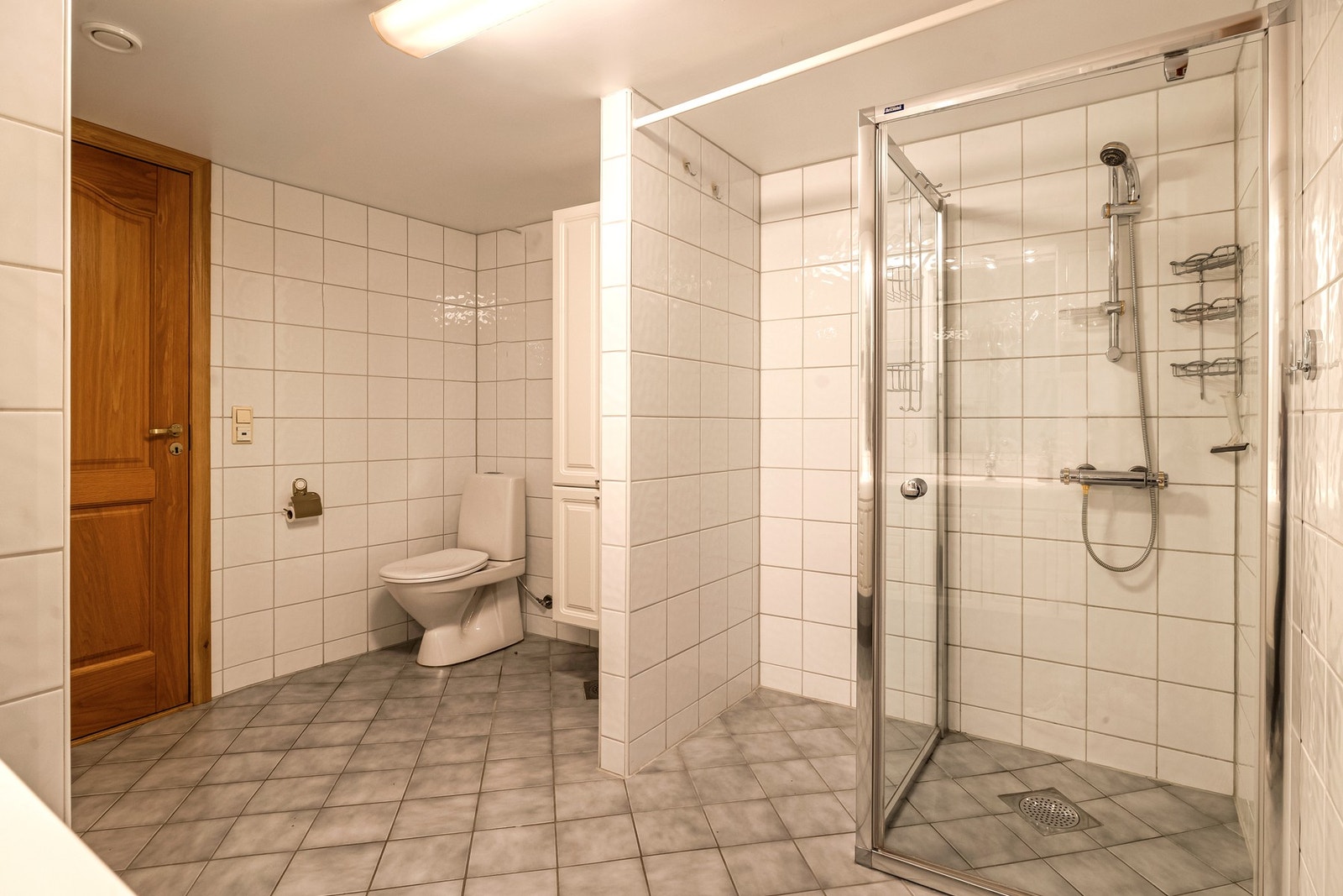 Badet varmes opp med elektriske varmekabler i gulv og har innredning med toalett, servant med belysning og dusjhjørne med dører. Galleribilde