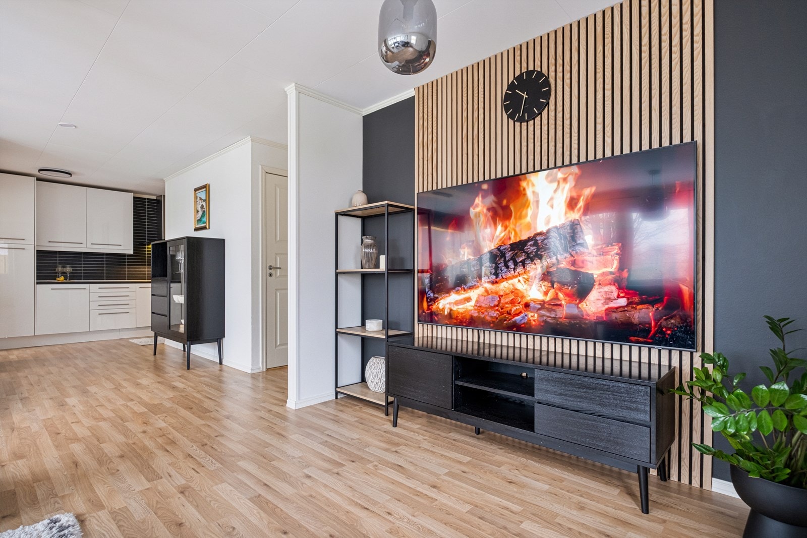 Stuen har en moderne innredning med en dekorativ veggpanel bak mediaområdet. Galleribilde