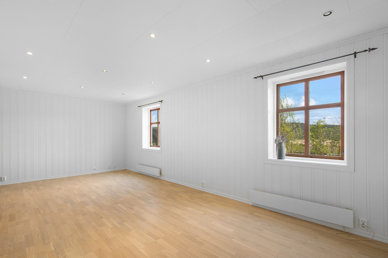 Lys og romslig kjellerstue med downlights i taket og panel på veggene. Galleribilde
