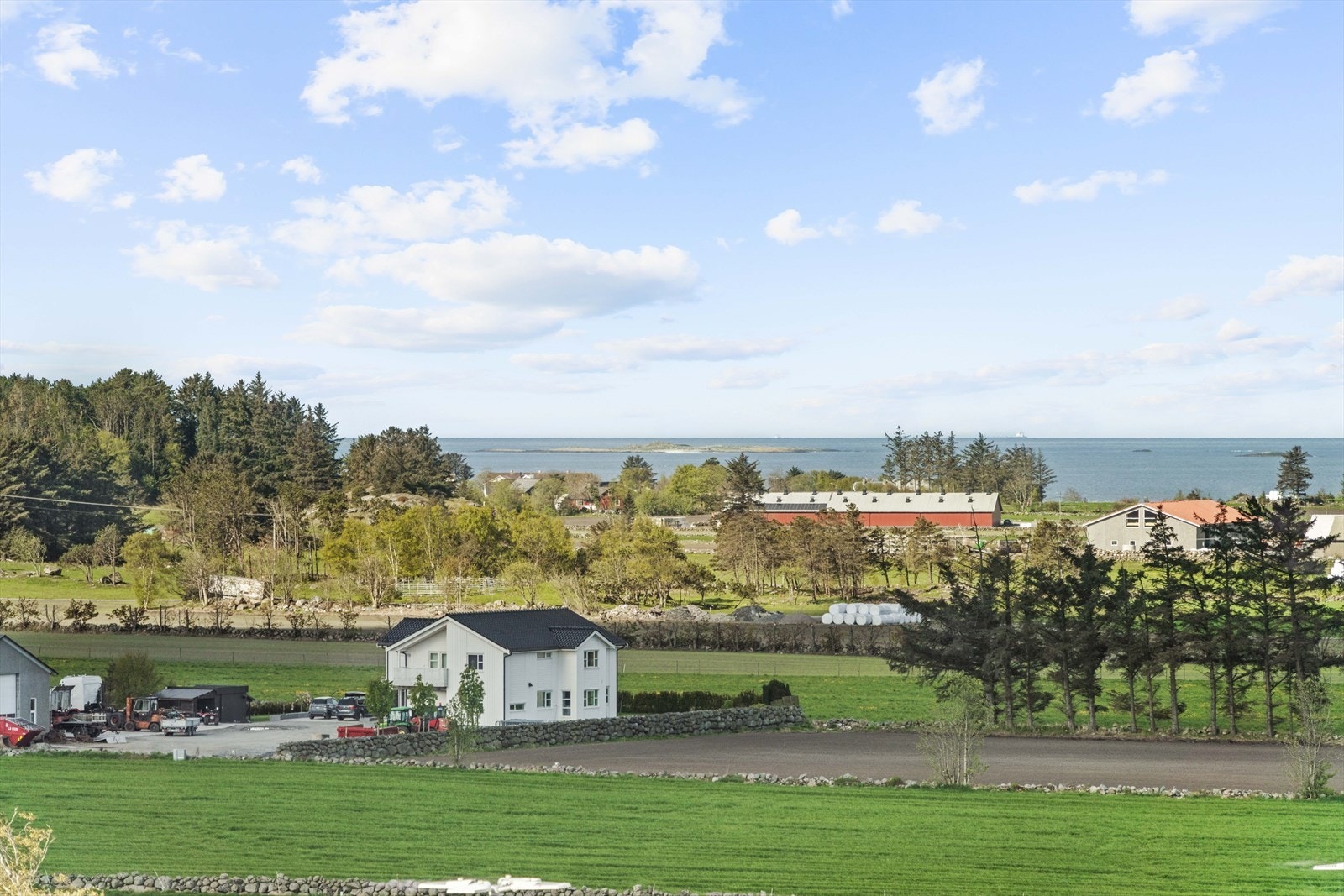 Utsikt mot det omkringliggende kulturlandskapet og sjøen i det fjerne. Galleribilde