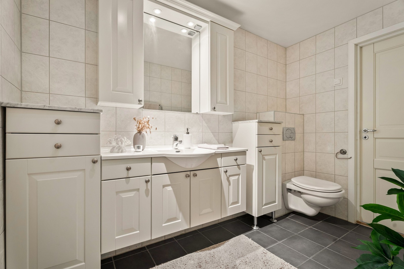 Badet er innredet med hvit baderomsinnredning med profilerte fronter. Galleribilde