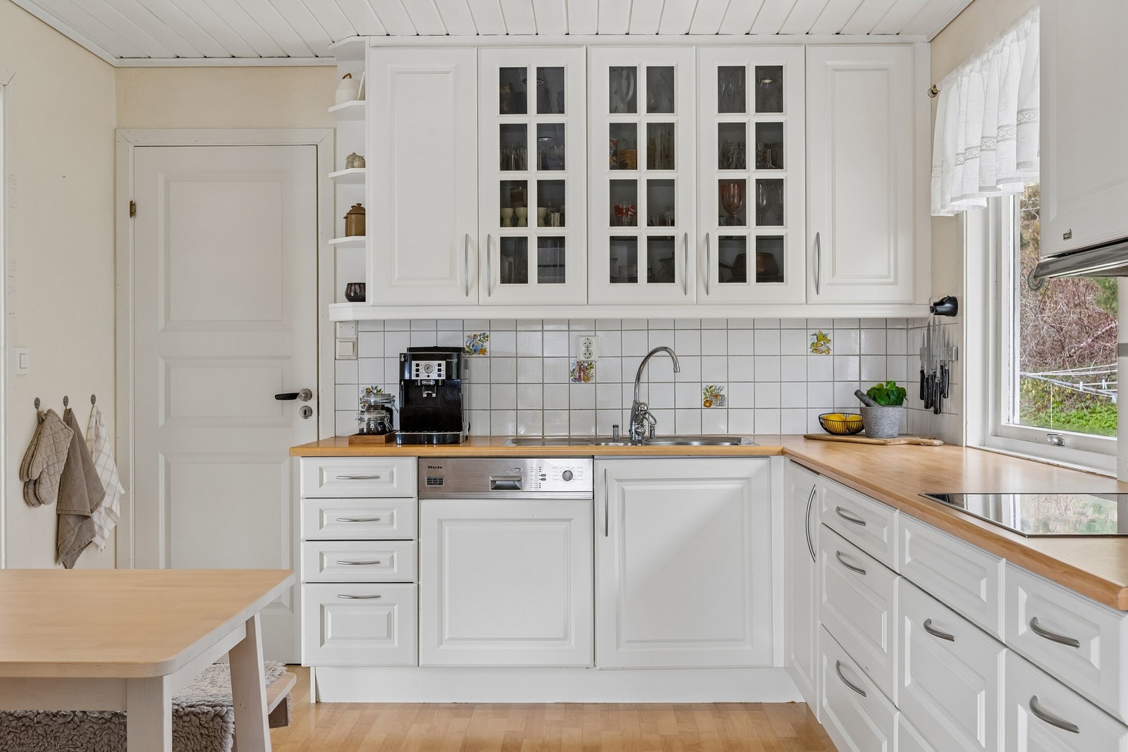 Kjøkkenet har en tidløs og klassisk stil med hvite fronter, trebenkeplate og god plass til matlaging. Galleribilde