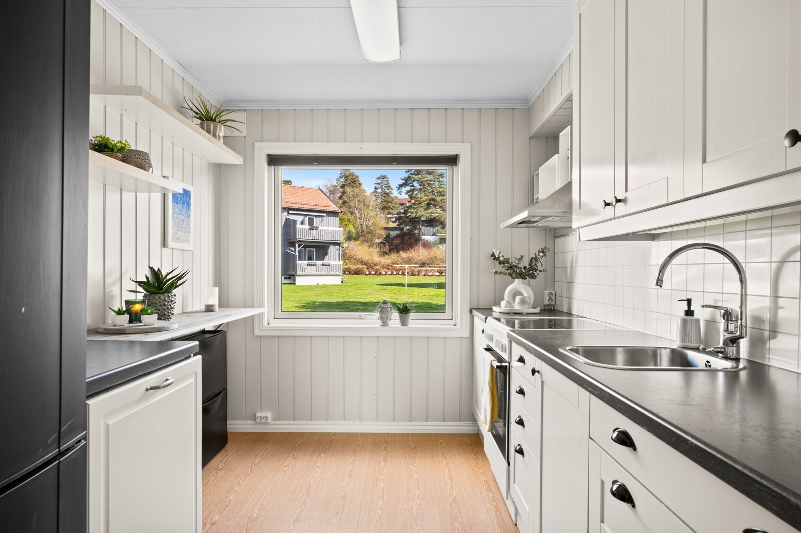 Kjøkkeninnredning med profilerte fronter og benkeplate i laminat. Kjøkkenventilator har avtrekk ut. Galleribilde
