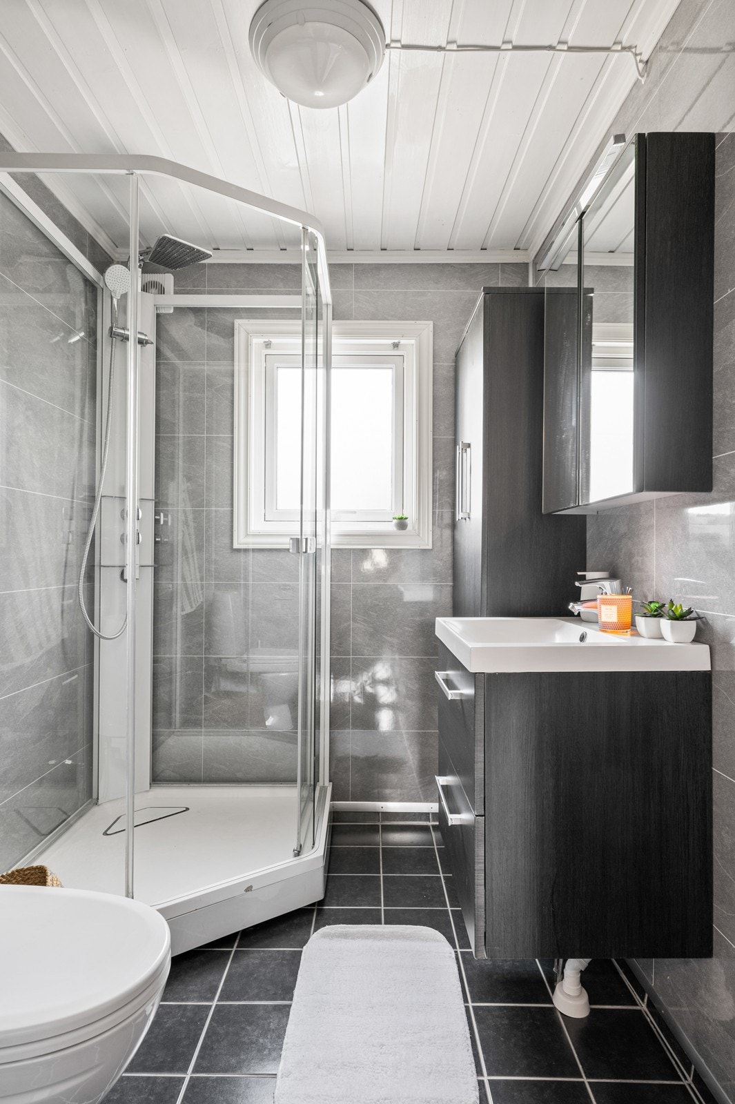 Badet er innredet med moderne servant innredning, høyskap og speilskap. Galleribilde