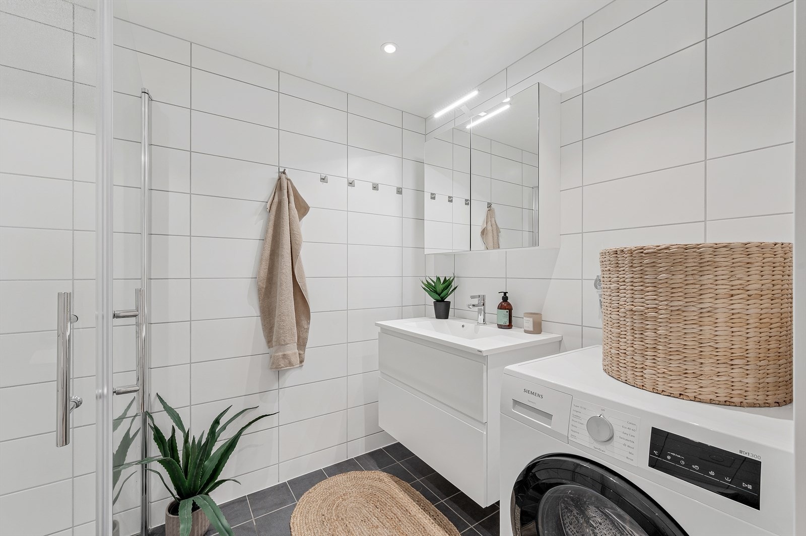 Badet er innredet med vegghengt toalett og en moderne baderomsinnredning med speilskap. Opplegg og plass for vaskemaskin Galleribilde