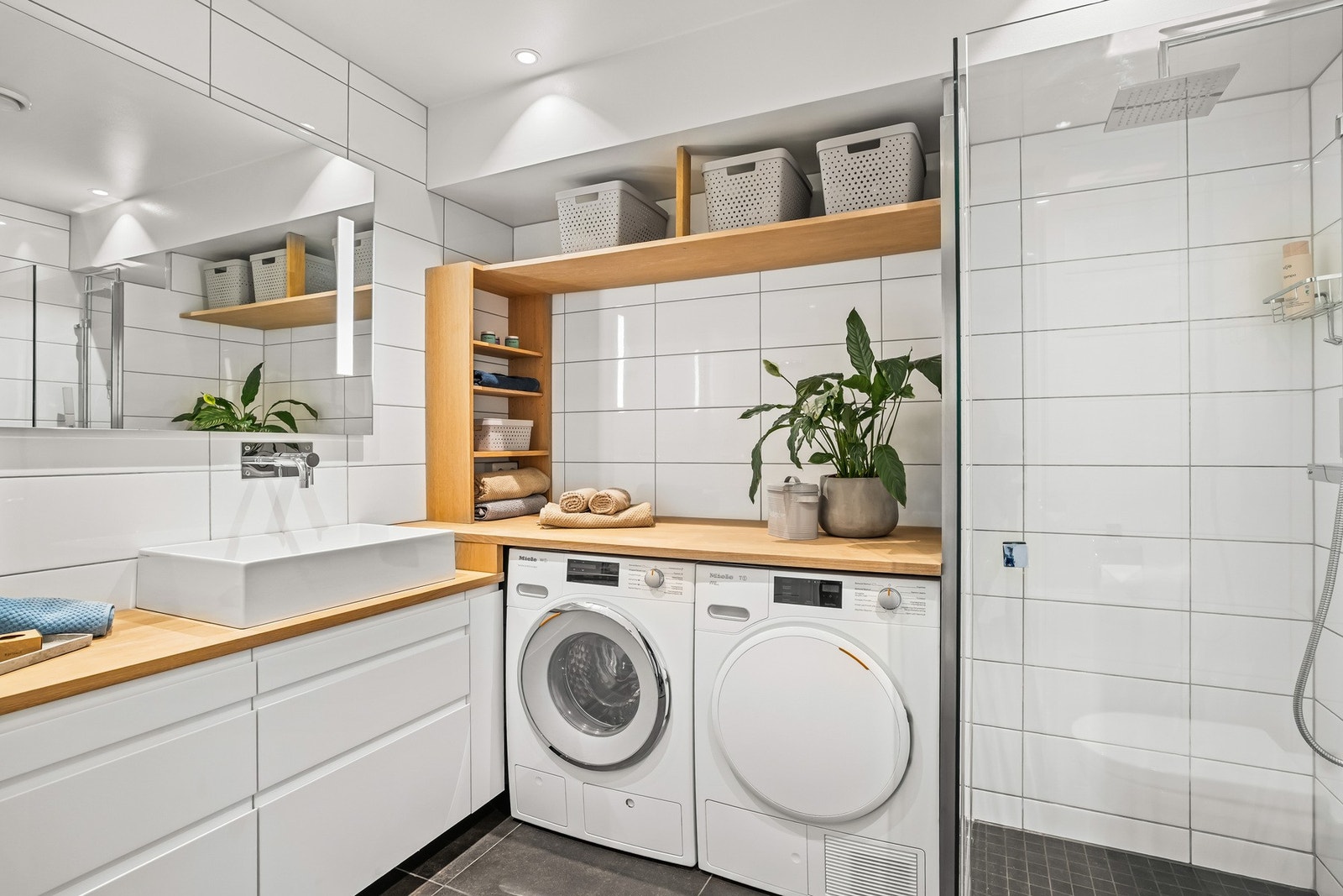 Badet fremstår stilrent med flislagte overflater, tidløs innredning, gulvvarme og opplegg for vaskemaskin/tørketrommel. Galleribilde