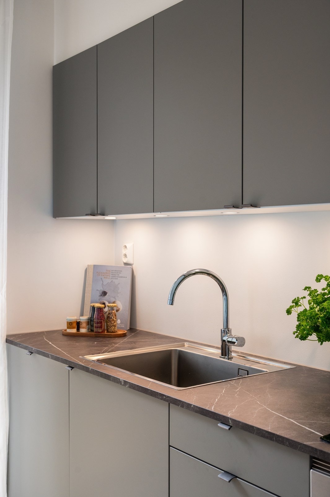Kjøkken med stilrene folierte fronter og benkeplate med underlimt vaskekum og ettgreps blandebatteri. Galleribilde