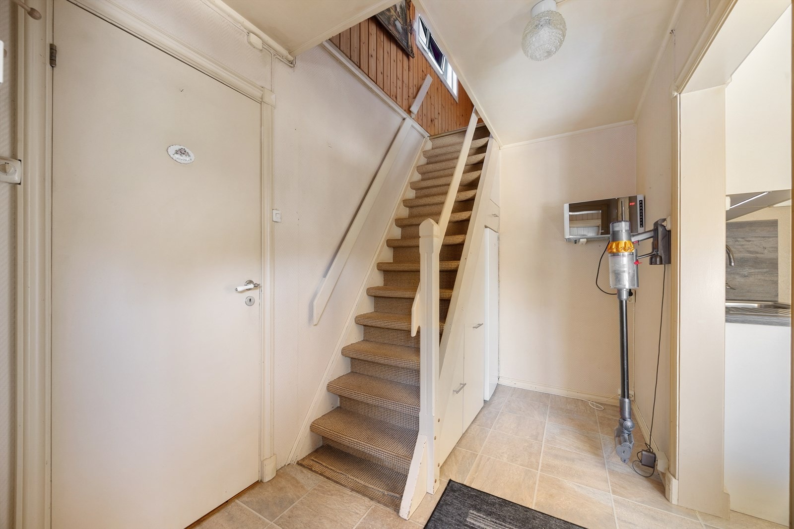 Fra gangen fører en malt tretrapp med teppe i trinnene opp til loftsetasjen. Galleribilde
