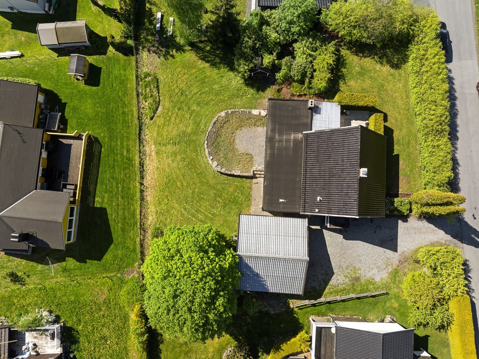 Tomten er pent opparbeidet med plen og hekk som rammer inn eiendommen. Galleribilde