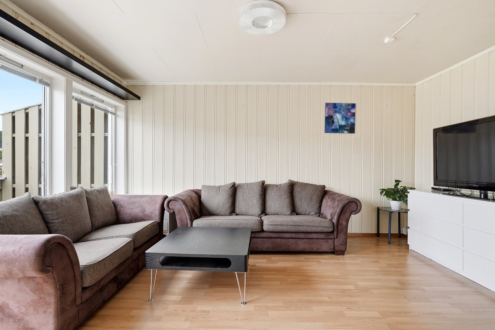 Rommet har plass til en sofagruppe og mediamøbler. Overflatene består av panelplater på veggene og laminat på gulvet. Galleribilde
