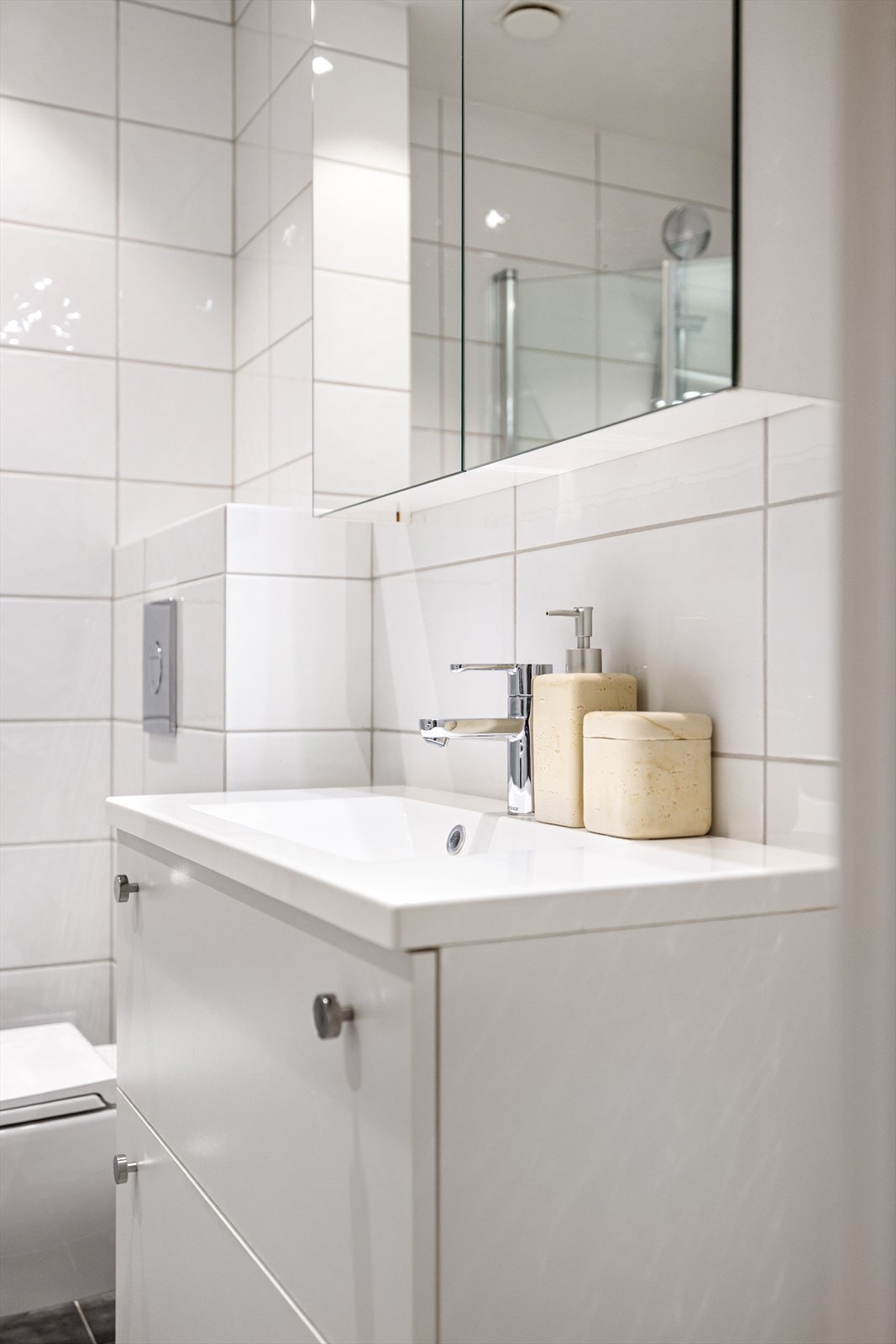 Badet er utstyrt med veggmontert wc, servant, dusjhjørne og opplegg for vaskemaskin. Galleribilde