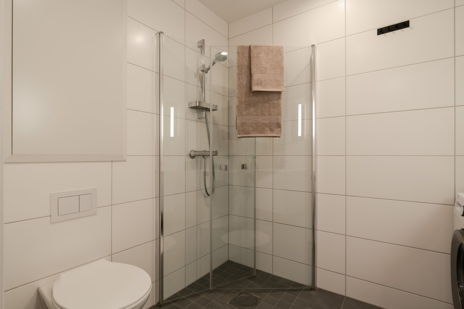 Badet er ca. 4 m² og fremstår moderne og praktisk innredet. Rommet har flislagte vegger og flislagt gulv, med en tidløs kombinasjon av lyse veggfliser og mørkere gulvfliser. Galleribilde