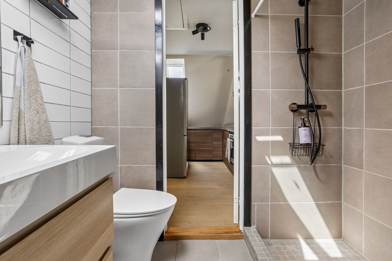 Badet har en praktisk dusjnisje med mosaikkfliser og en elektrisk styrt avtrekksvifte i himlingen. Galleribilde
