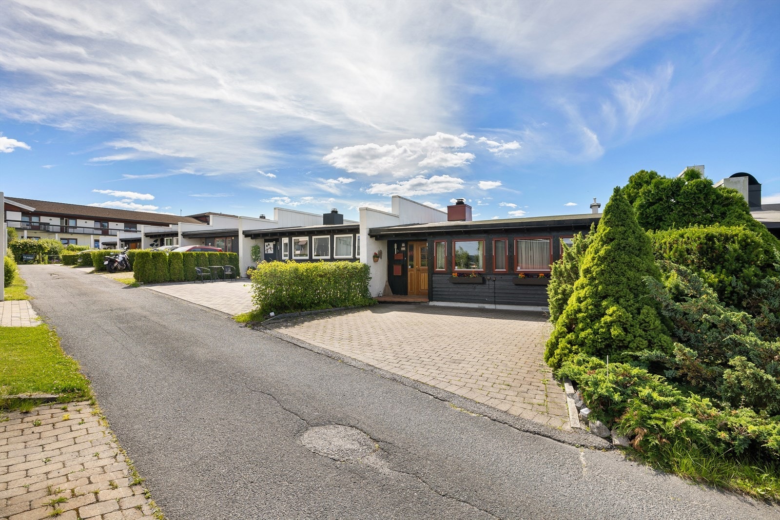 Steinbelagt inngangsparti med biloppstillingsplasser. Galleribilde