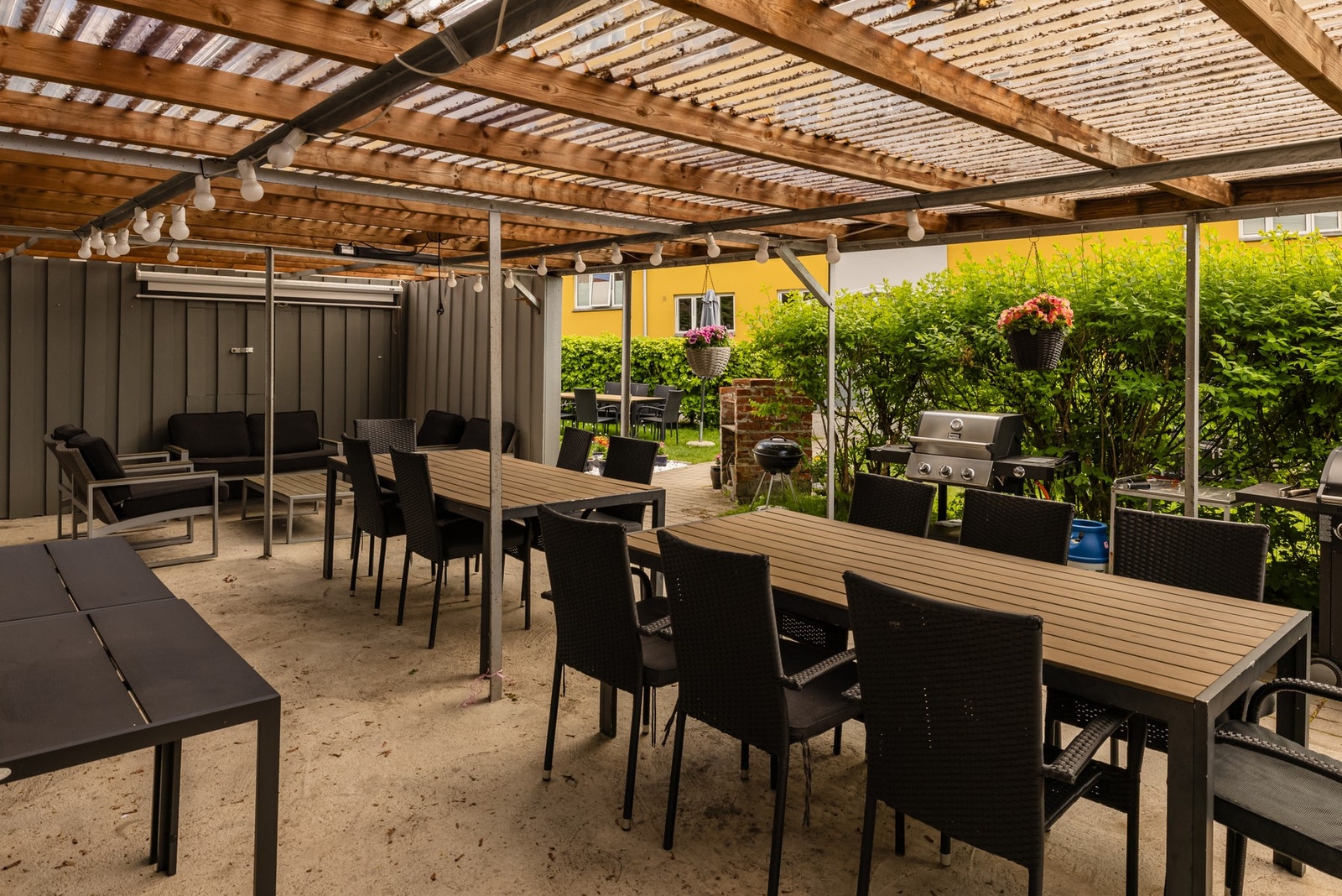 Overbygget uteplass med flere sittegrupper og grill. Galleribilde