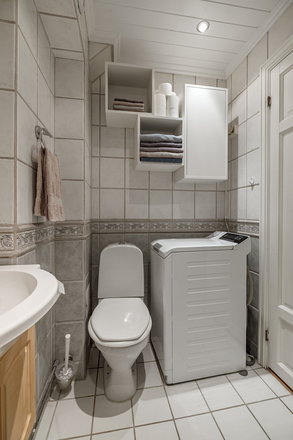 I hjørnet er det plass og opplegg for vaskemaskin, samt oppbevaringsplass i vegghengte hyller og skap over. Galleribilde