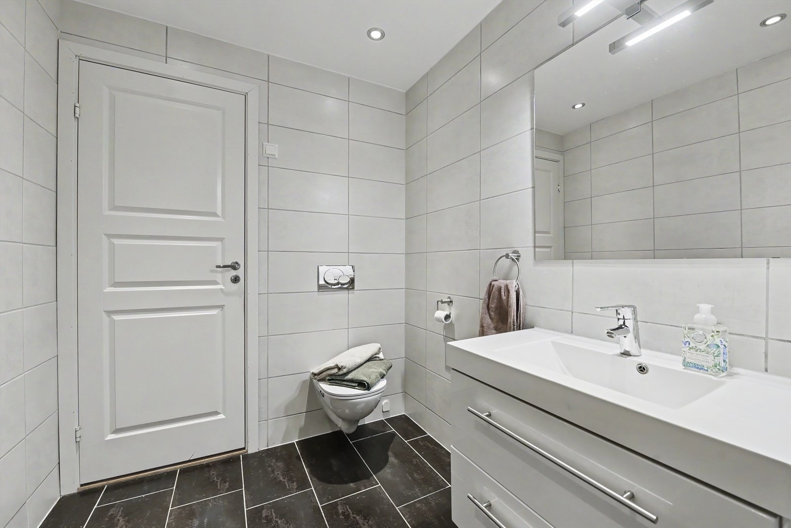 Badet er utstyrt med vegghengt toalett og servantskap med gode oppbevaringsmuligheter. Galleribilde