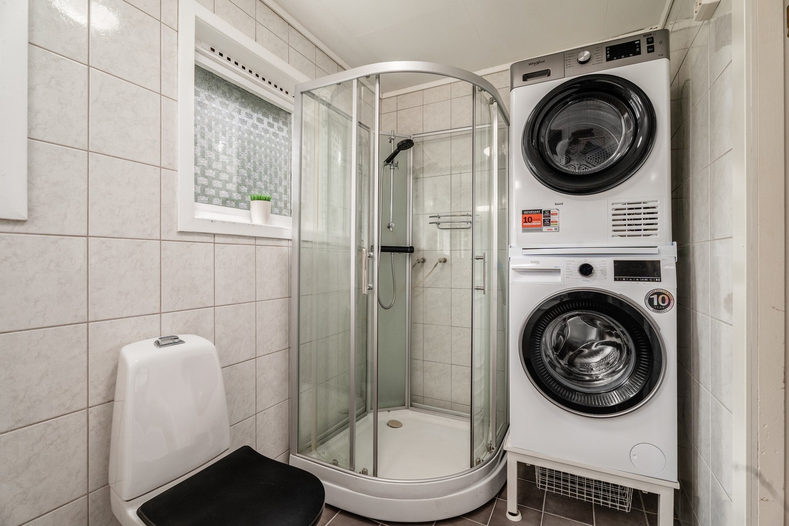 Badet er helfliset og utstyrt med servant med innredning, toalett, dusjkabinett samt opplegg for vaskemaskin. Galleribilde