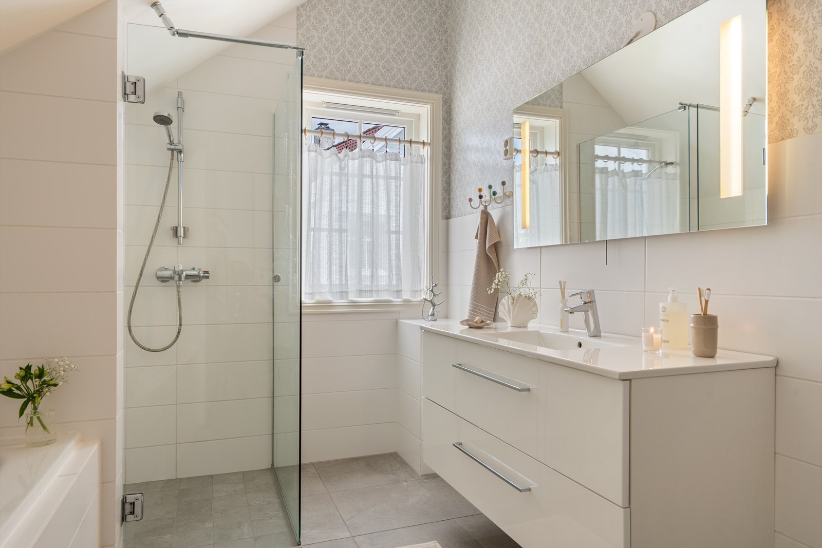 Badet har fliser på gulv, dusjsone og moderne baderomsinnredning. Galleribilde