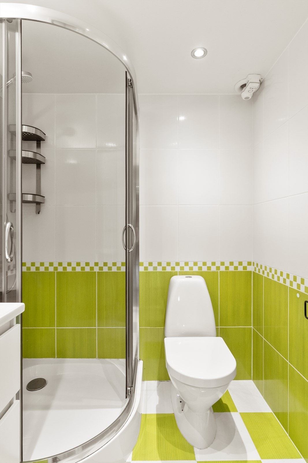 Badet er utstyrt med dusjkar, toalett på gulv og servant med underskap. Galleribilde