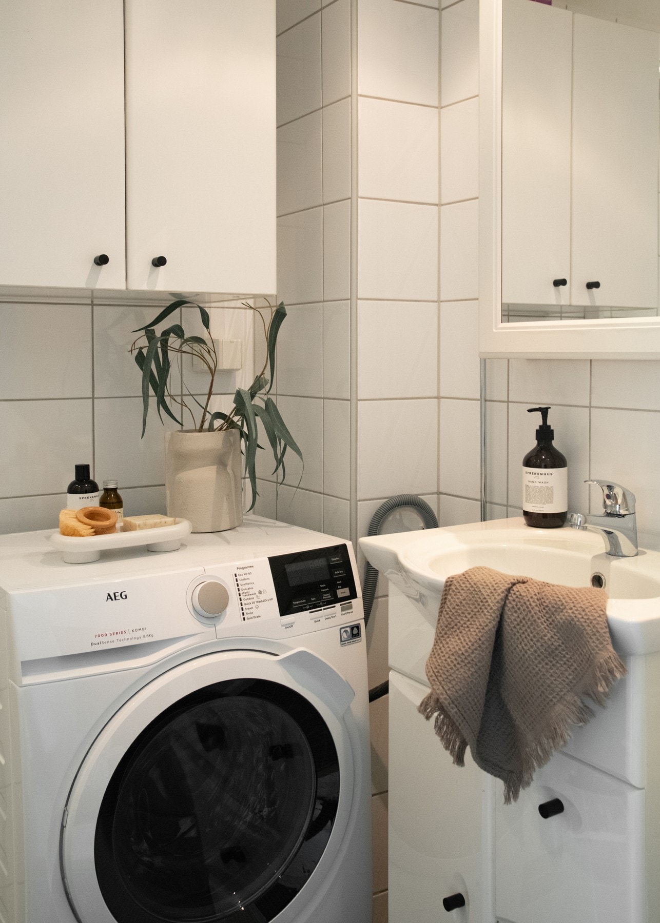 Badet utstyrt med dusjhjørne med glassdører og vegghengt dusjarmatur, vegghengt toalett samt opplegg for vaskemaskin. Galleribilde