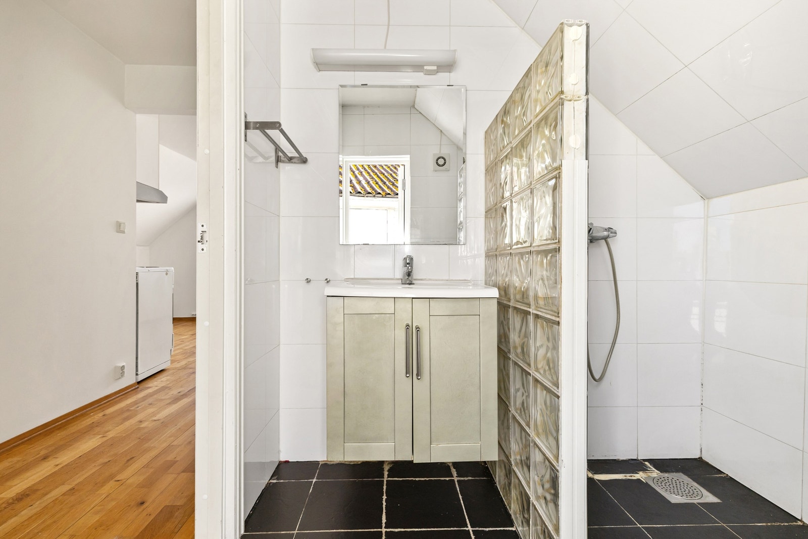 Badet har flislagt gulv, dusjhjørne og servantinnredning. Galleribilde