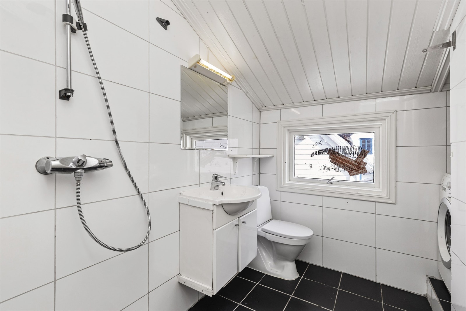 Badet har flislagt gulv, panel i taket og dusjløsning. Galleribilde
