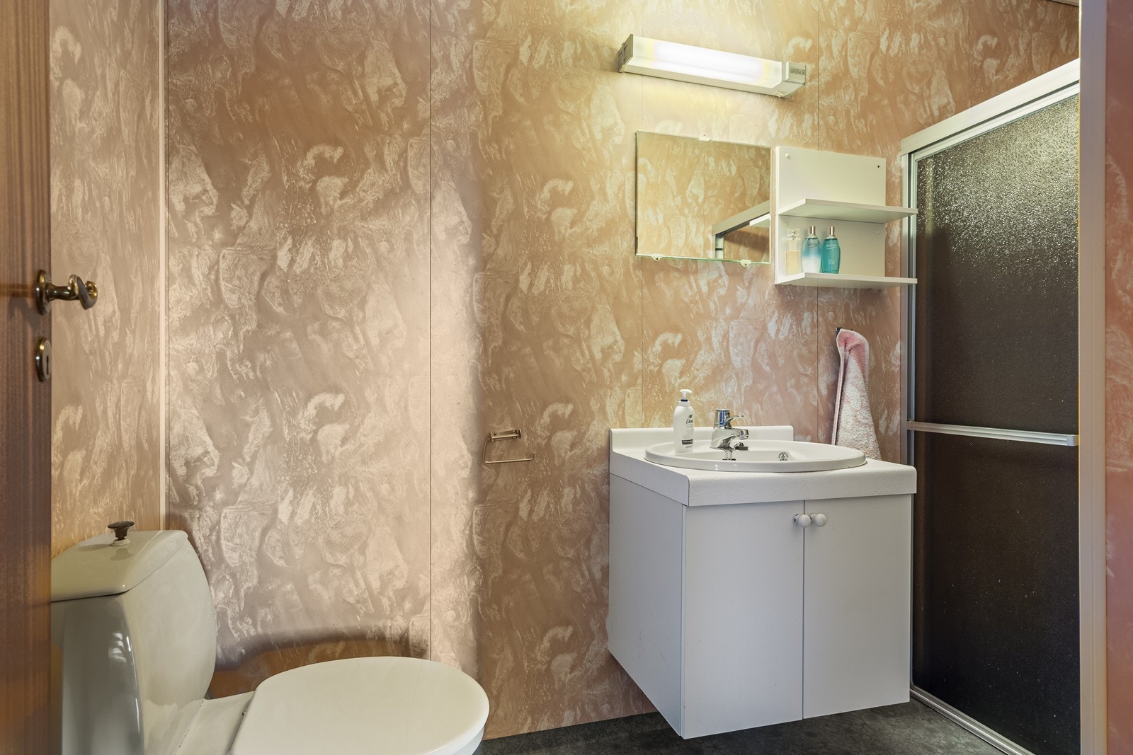 Badet inneholder servant i møblement med vegghengt skap, speil og belysning, toalett og dusjkabinett. Galleribilde