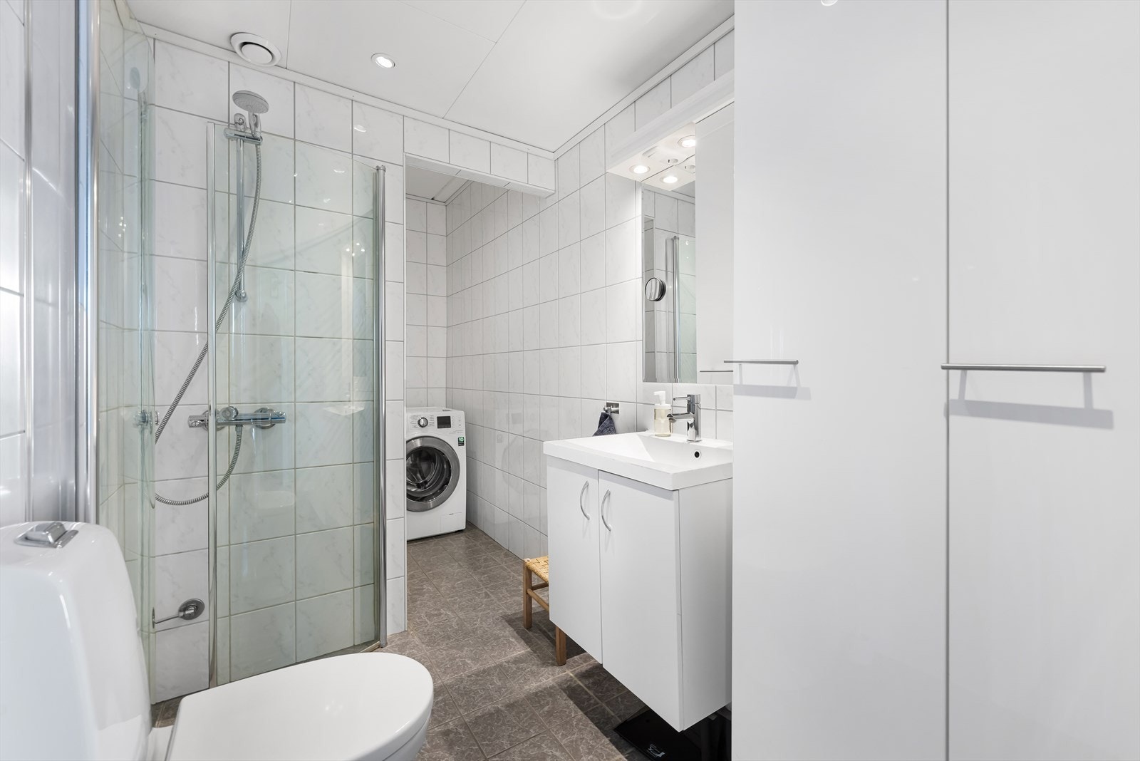 Badet har flislagt gulv, toalett og dusjhjørne med innfellbare vegger. Galleribilde