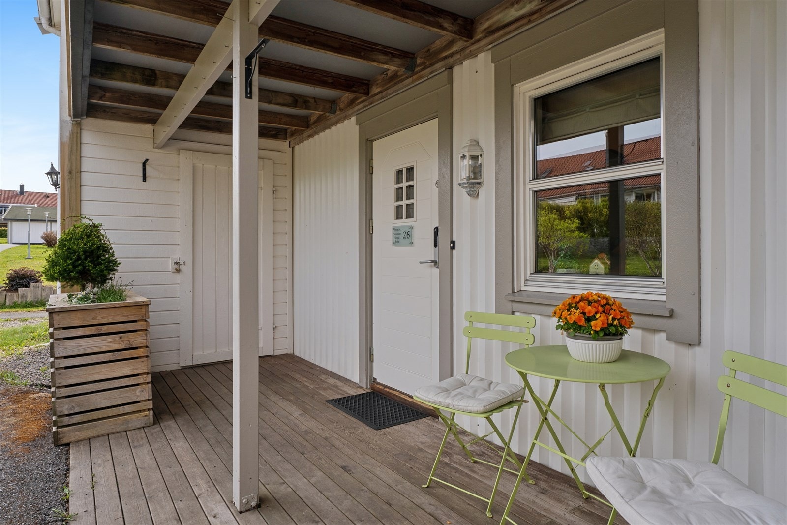 Overbygget inngangsparti med en hyggelig treplatting og plass for en liten sittegruppe. Galleribilde