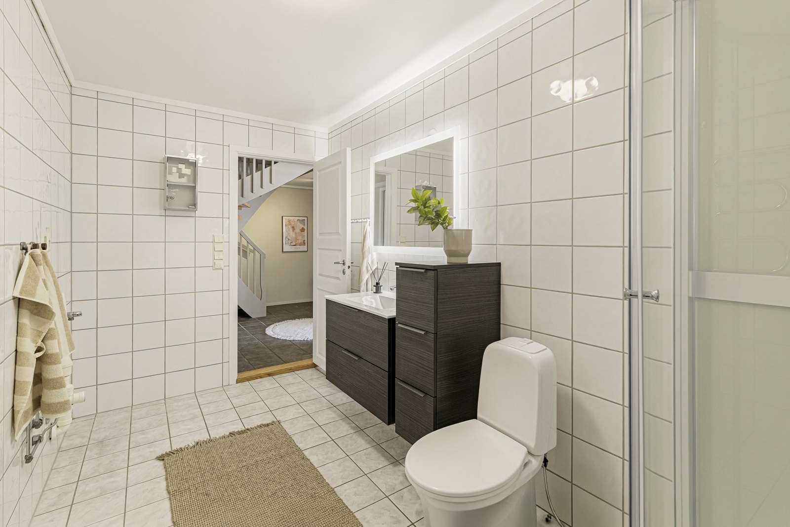 Badet har servant i innredning, dusjkabinett og gulvsatt toalett med varmekabler i gulv Galleribilde