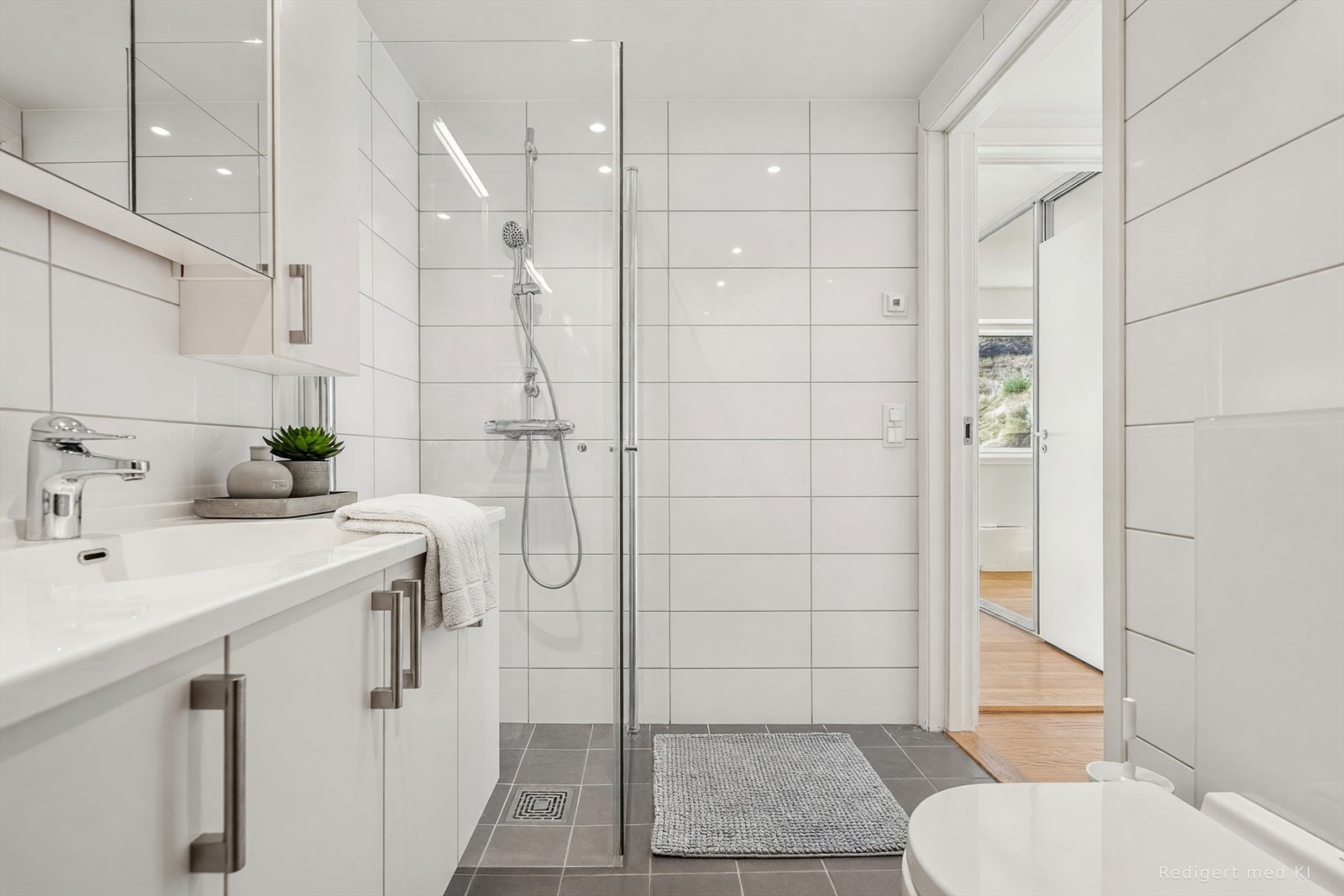 Badet er ellers utstyrt med dusjhjørne, vegghengt toalett og baderomsinnredning med nedfelt servant. I tillegg har man vaskeromsløsning med opplegg for vaskemaskin og varmtvannsbereder bak skyvedører (vi gjør oppmerksom på at bildet er digitalt møblert). Galleribilde