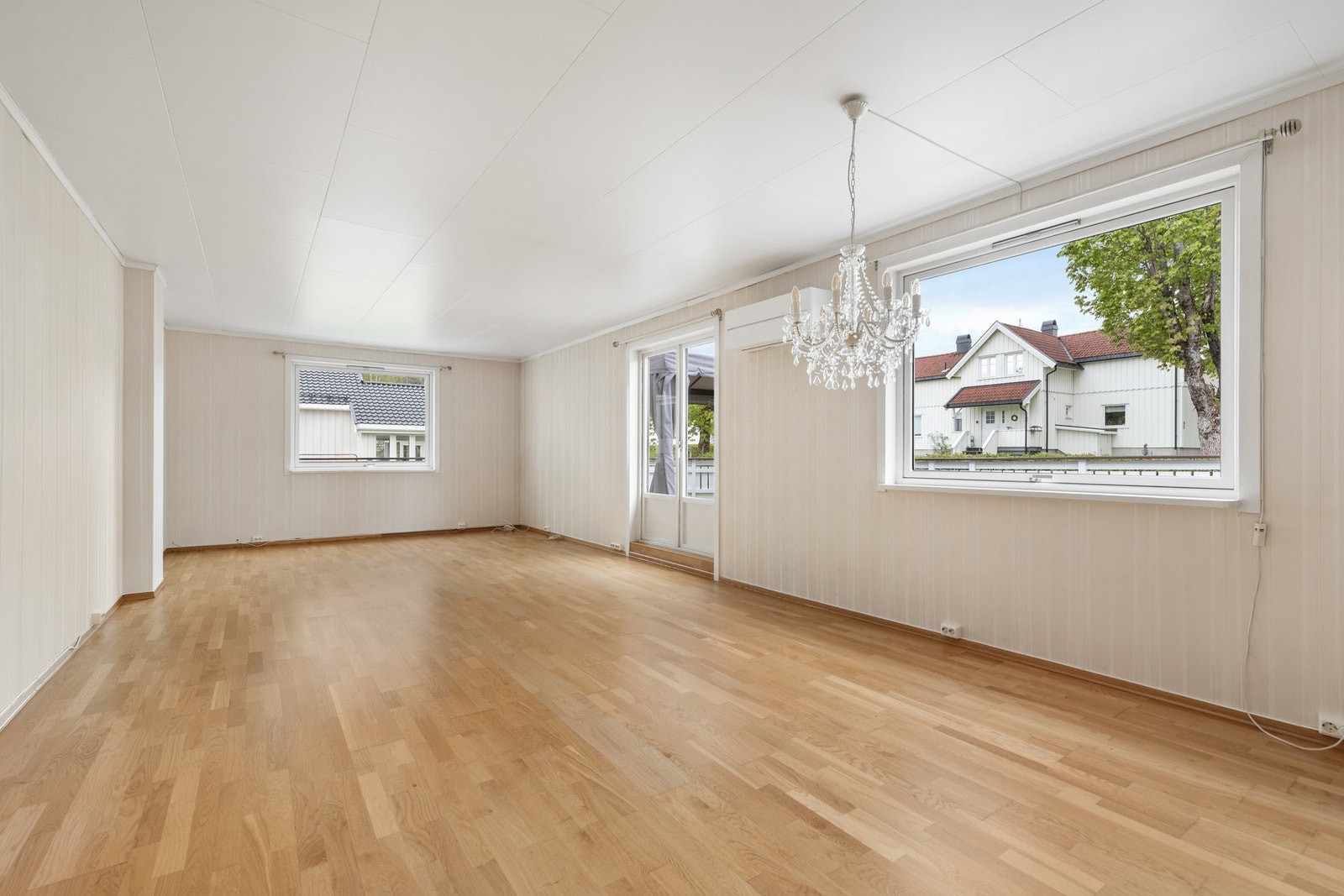 Lys og stor stue med 3-stavs parkett, tapet på vegger og takplater i himling Galleribilde