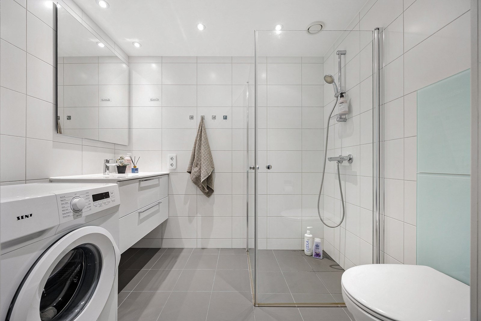 Badet er innredet med servant med skuffeseksjon, vegghengt toalett og opplegg for vaskemaskin. Galleribilde