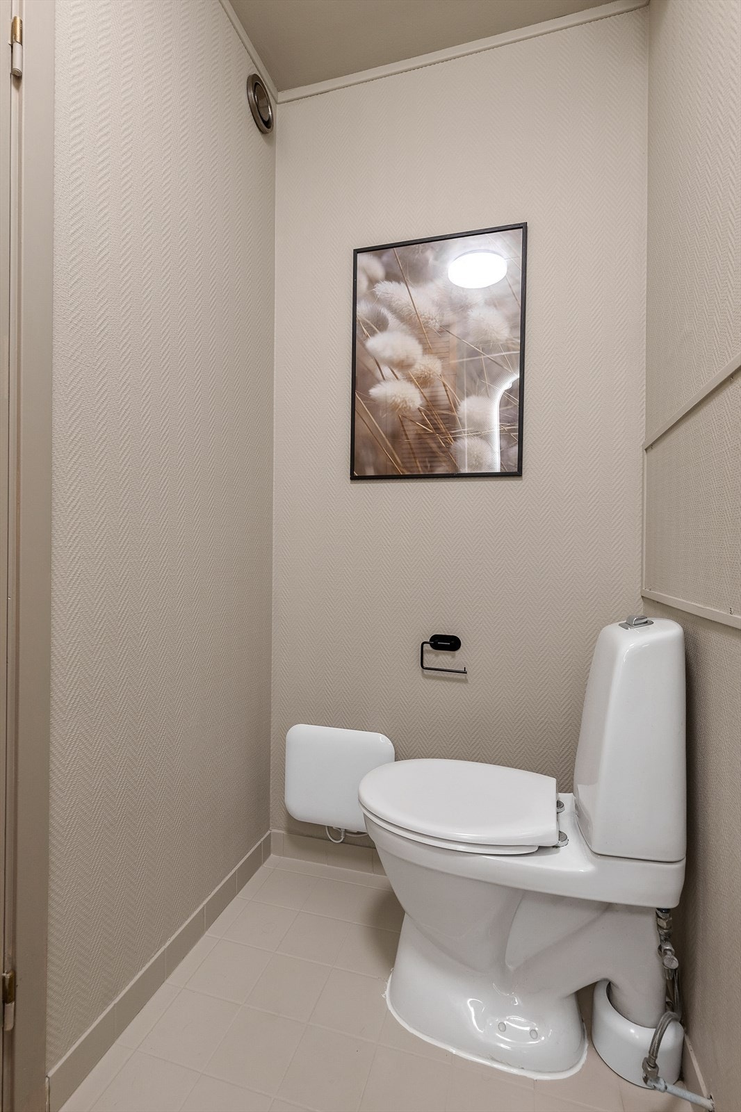 Toalettrom med tilgang fra badet og entreen. Gulvflate belagt med fliser. Tapetserte veggflater. Malte flater i himling. Vegghengt servantinnredning. Gulvstående toalett. Mekanisk avtrekk med ventil i vegg. Galleribilde