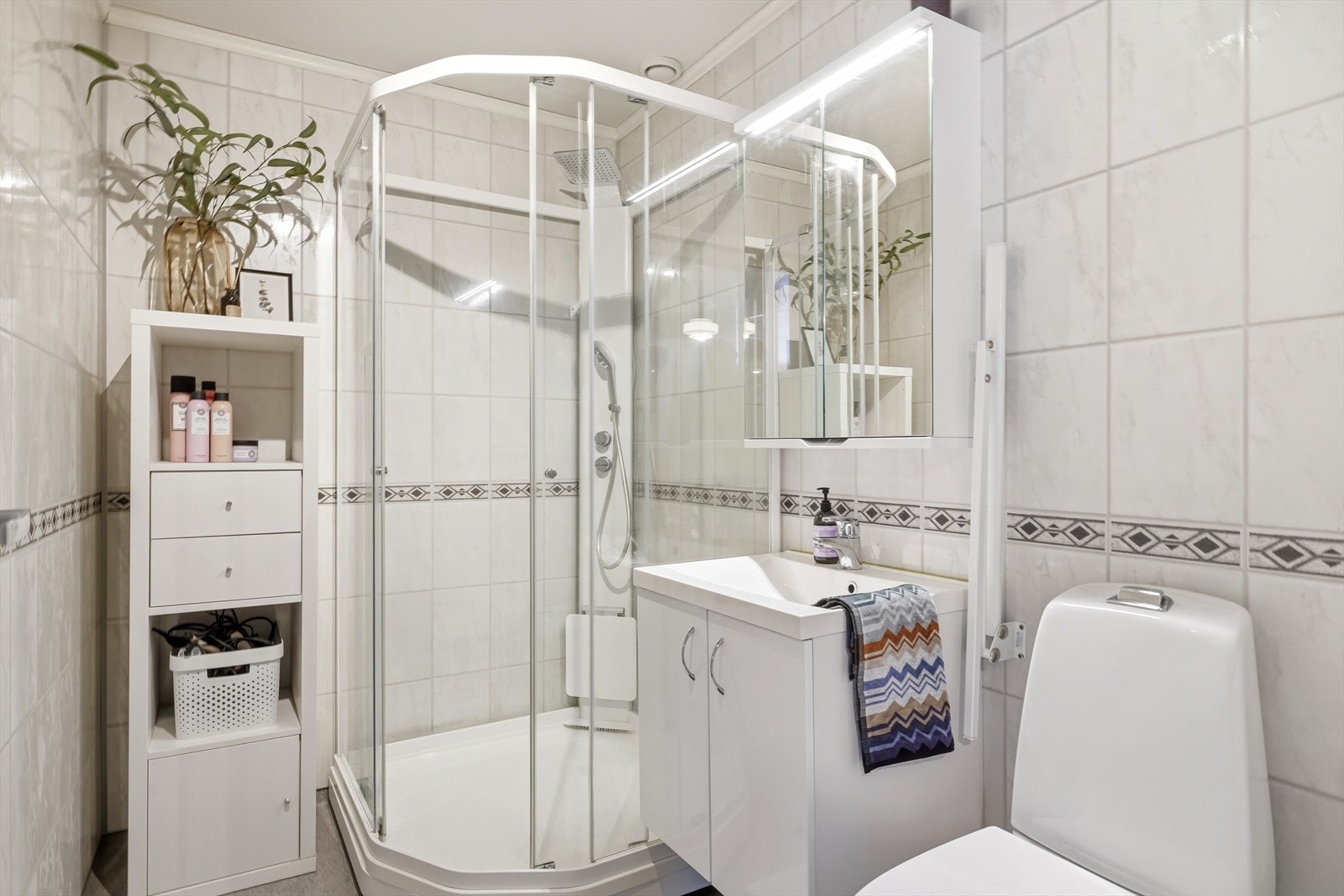 Badet er innredet med dusjkabinett, servant med underskap og toalett. Galleribilde