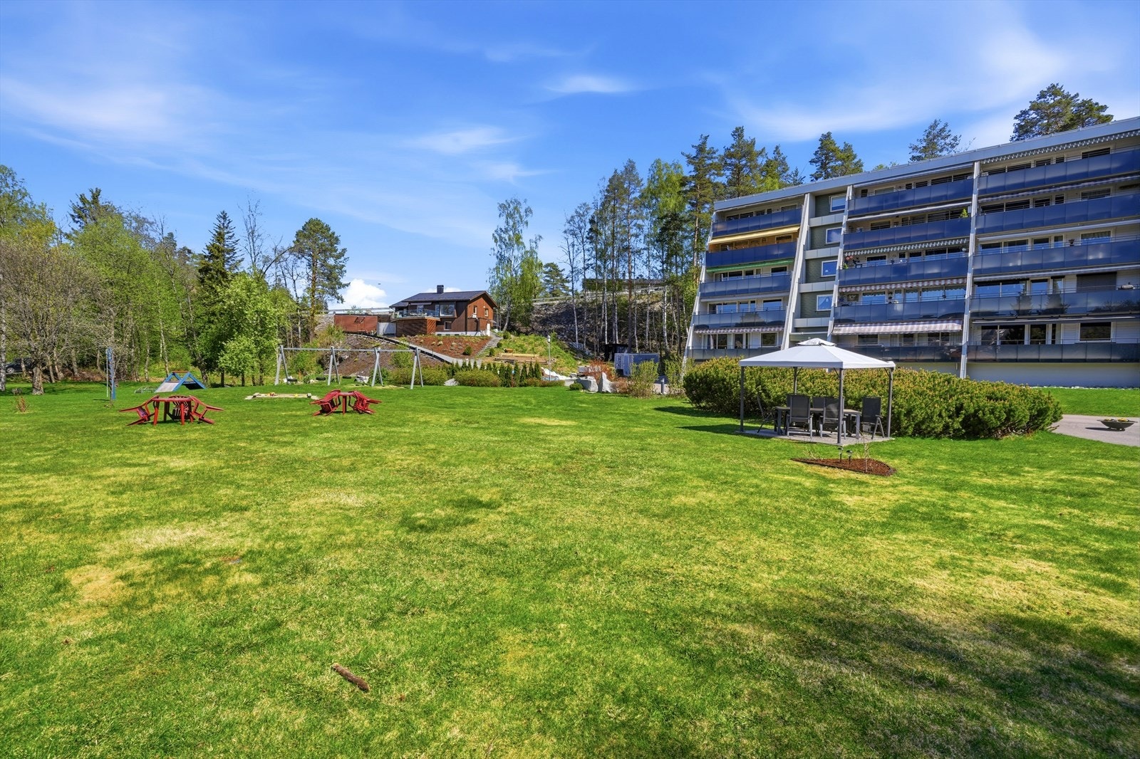 Store, grønne fellesarealer med lekeapparater og sittegrupper. Galleribilde