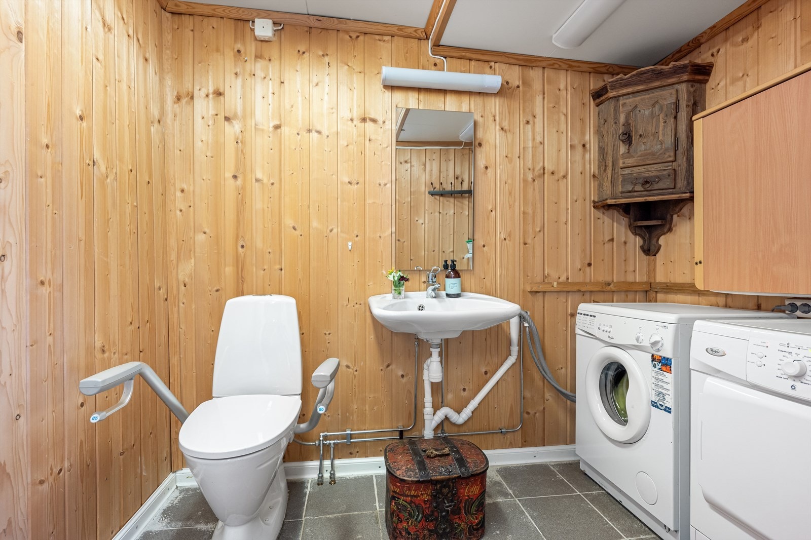 Ved entréen er det etablert et toalettrom med granittfliser på gulv, gulvvarme og panelte vegger som gir rommet et lunt preg. Himlingen har takessplater. Galleribilde