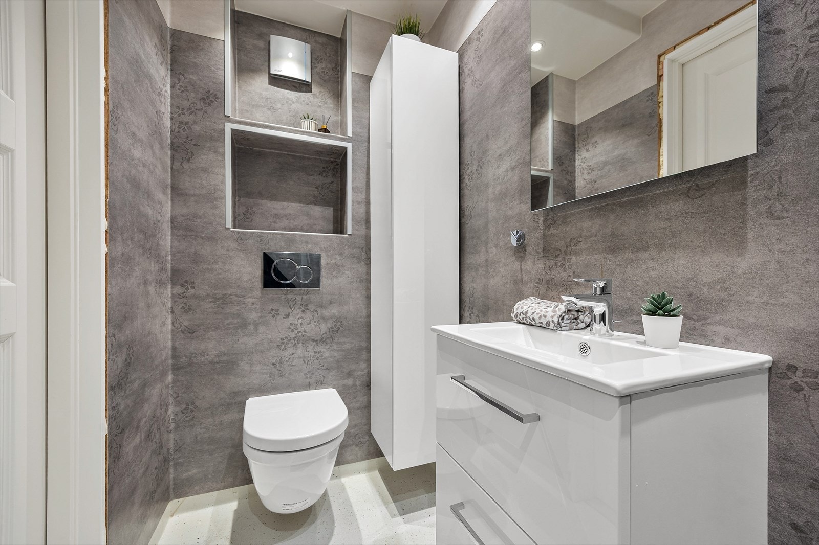 Badet har vinylbelegg på gulv, våtromstapet på veggene og vegghengt toalett. Galleribilde