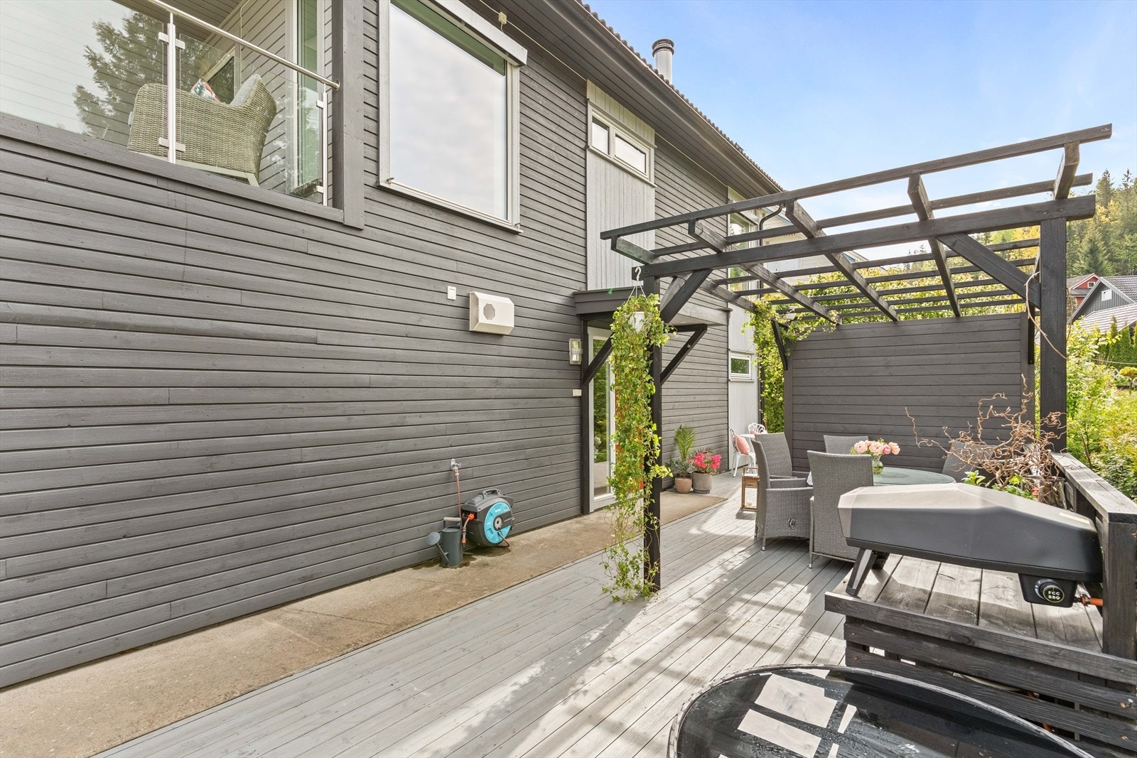 Lun uteplass langs boligen med plass til sittegruppe. Pergola og beplantning gir en skjermet og trivelig atmosfære. Det er svært gode solforhold på uteplassene. Galleribilde