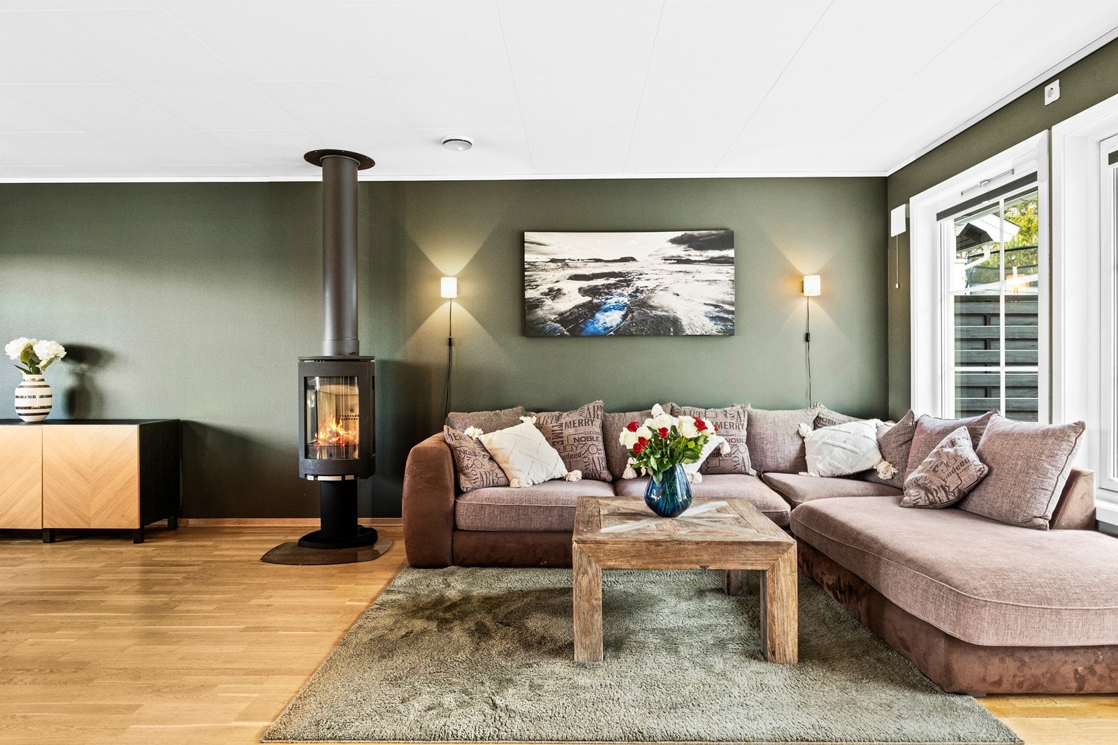 Midt i rommet står en flott vedovn for ekstra varme og hygge på kjølige dager. Galleribilde
