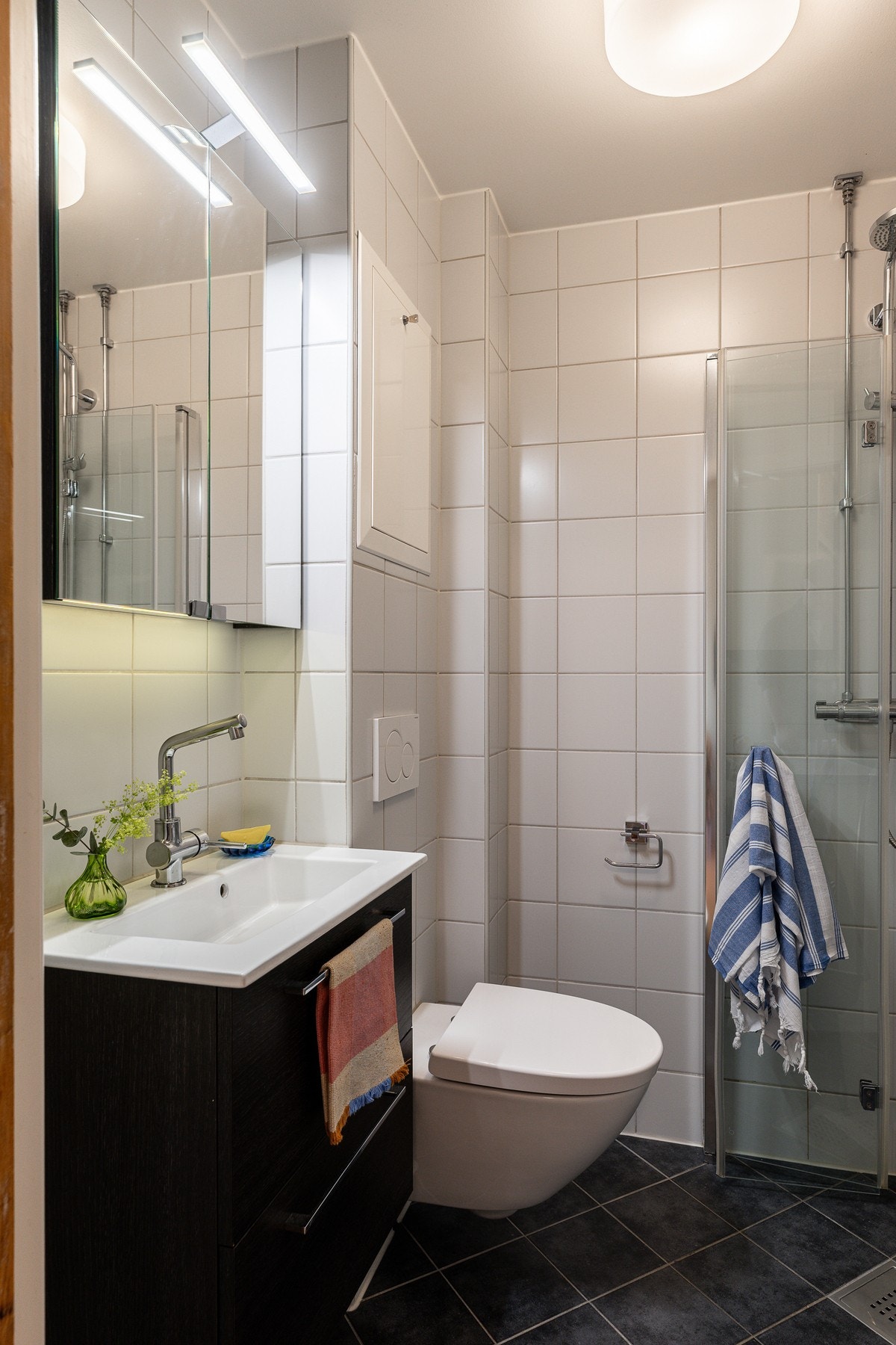 Badet er innredet med vegghengt toalett, servant, speilskap med lys og dusjhjørne med svingbare glassdører, samt opplegg for vaskemaskin. Galleribilde