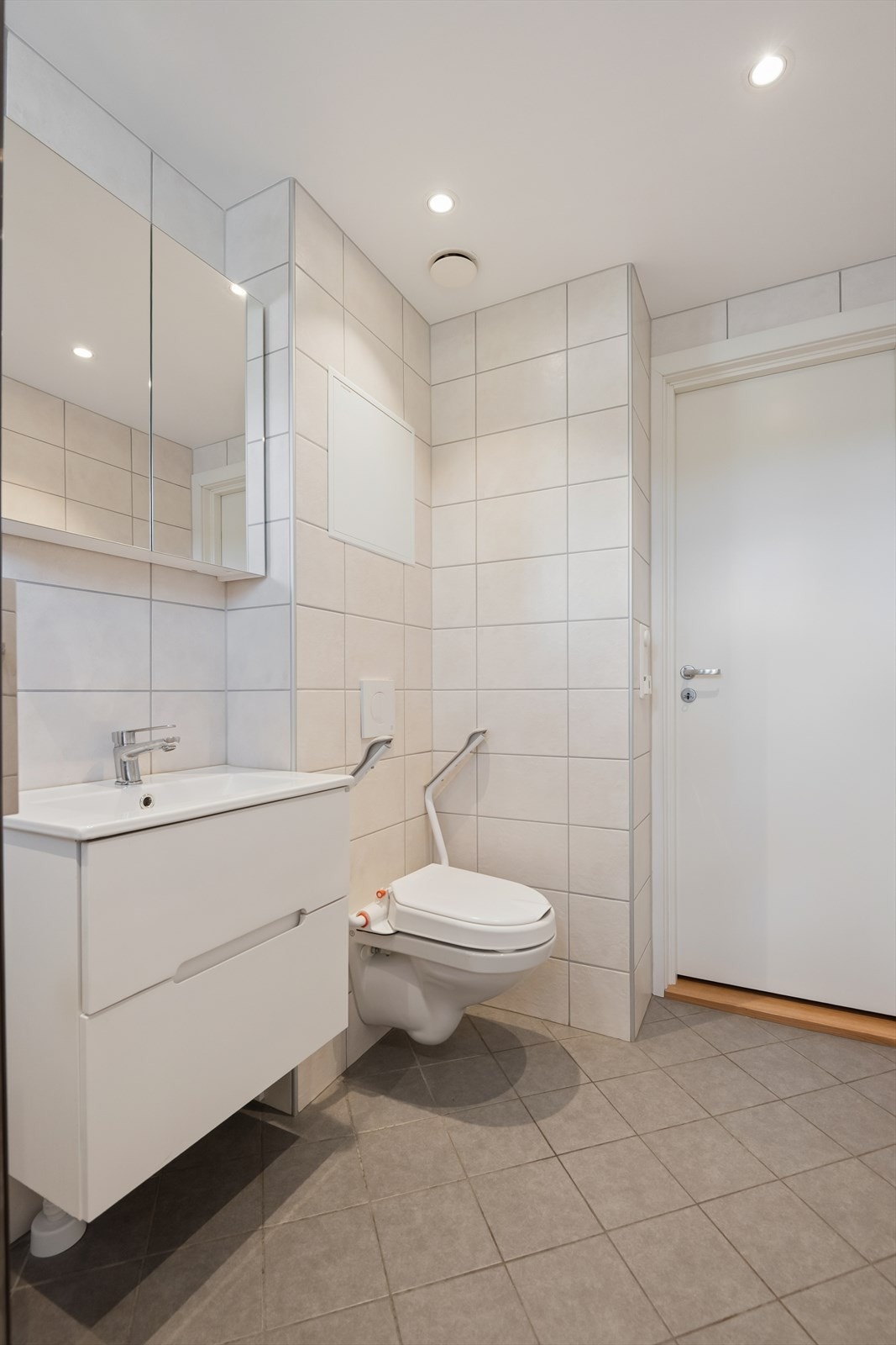 Badet har vask med underskuffer, vegghengt toalett, innfellbare dusjvegger og uttak til vaskemaskin Galleribilde